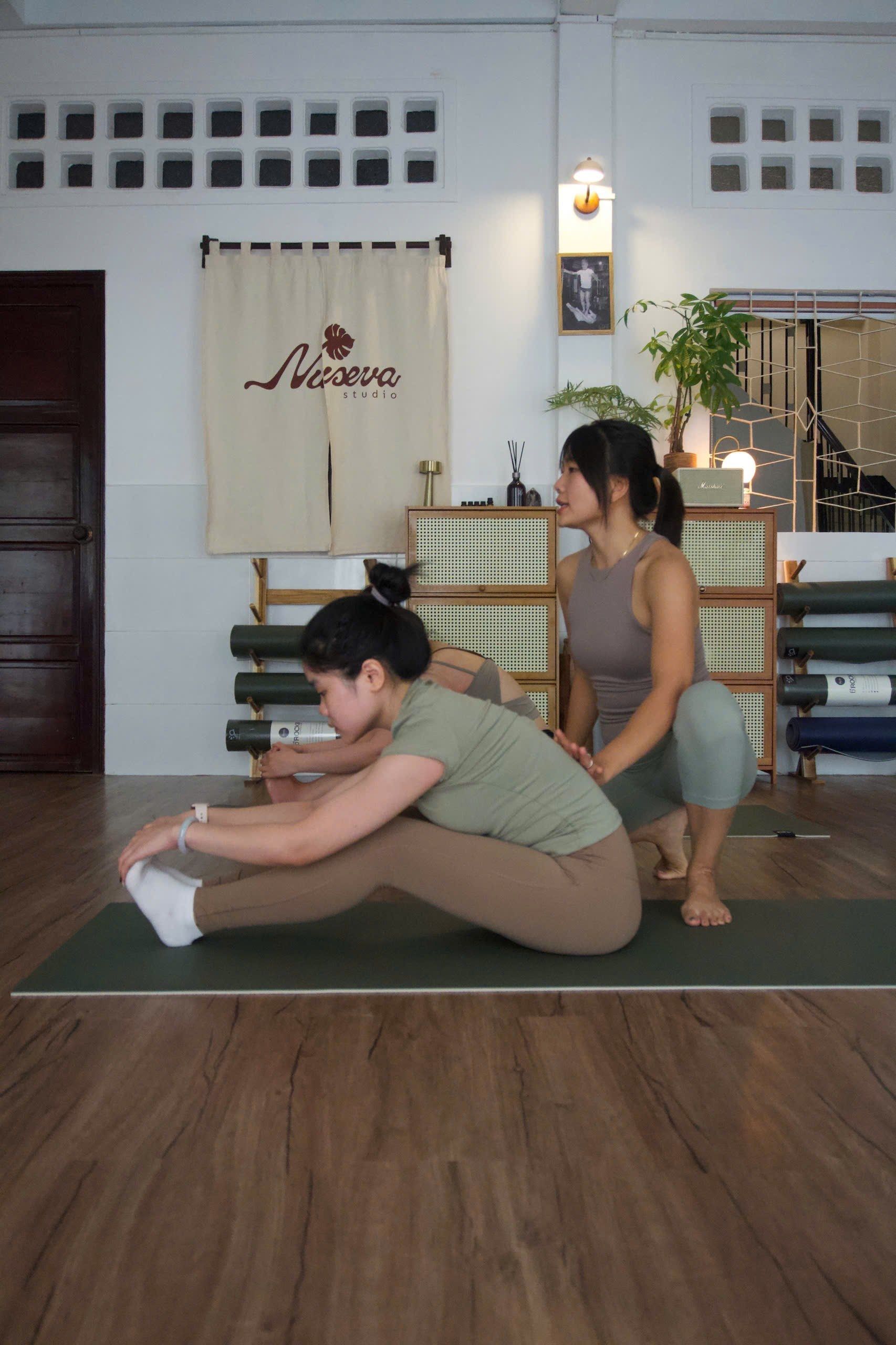 Huấn luyện viên đỡ lưng học viên lớp Yoga